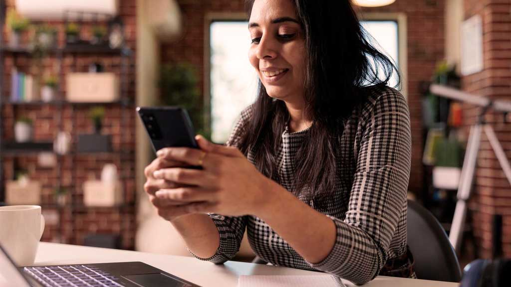 Mulher usando o WhatsApp para vendas em um ambiente de trabalho organizado